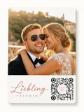 A custom wedding photo card featuring a printed photograph of a smiling couple at sunset, with the text 'Liebling STUDIO' in rose gold script and a black-and-white QR code on a white card with rounded corners.