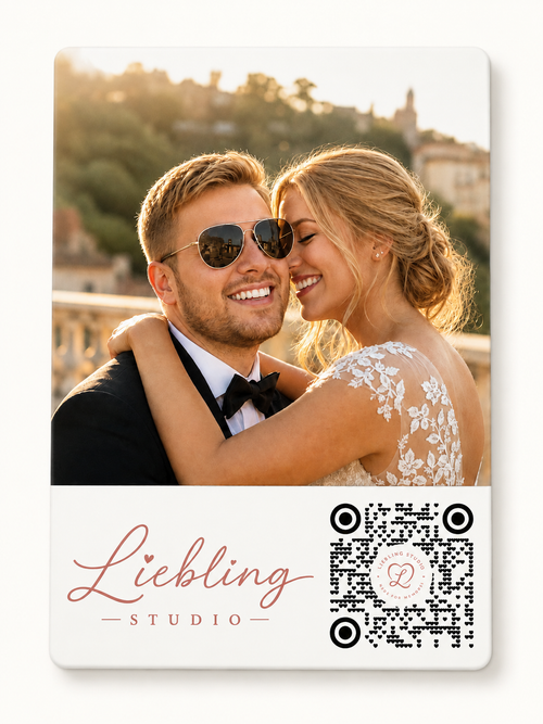 A custom wedding photo card featuring a printed photograph of a smiling couple at sunset, with the text 'Liebling STUDIO' in rose gold script and a black-and-white QR code on a white card with rounded corners.